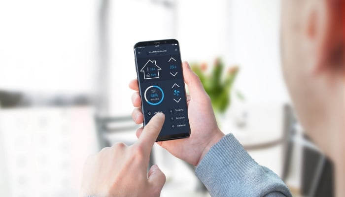 man using smart home controls on phone to adjust indoor temperature